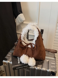 Detail of brown suede bucket bag with white faux fur trim and fluffy pompom charms