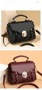 Detail of leather crossbody bag with snake-pattern panels and metal clasp closure