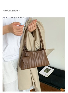 Detail of a brown woven leather tote bag with classic weave pattern and circular pendant