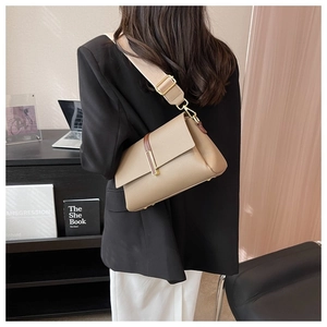Detail of khaki pebbled leather crossbody bag featuring a wide canvas strap and metal clasp