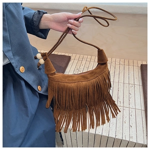 Detail of brown suede shoulder bag with long fringes and wooden bead accents