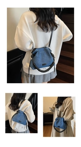 Detail of blue denim cloud bag with unique spiral handle and crossbody leather strap