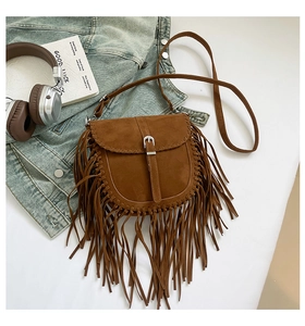 Détail du sac besace marron en daim avec longues franges et coutures décoratives lifestyle