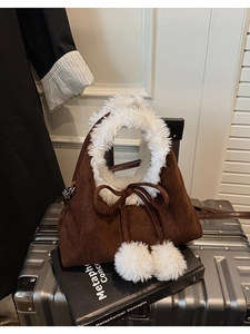 Detail of brown corduroy bucket bag with white faux fur trim and plush pom-poms