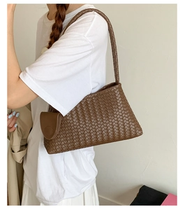 Detailed view of woven dark brown leather tote bag worn as a shoulder bag on a model