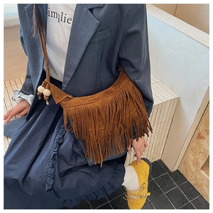 Detail of brown suede crescent bag featuring long fringe and decorative wooden beads