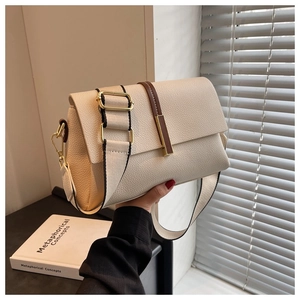Close-up of off-white lychee leather texture and gold metal buckle on a square bag