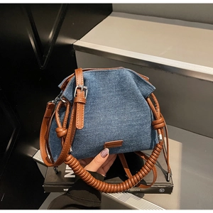 Close-up of denim bucket bag featuring a thick spiral woven handle and brown leather straps