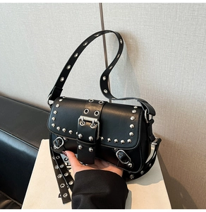 Detail of a punk style black leather underarm bag with silver rivets and metal buckle