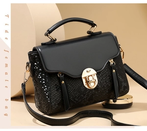 Close-up of black crossbody bag featuring snakeskin texture and golden turn-lock