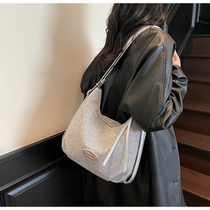 Chic grey leopard hobo bag with sleek metal emblem on a stylish model in leather coat