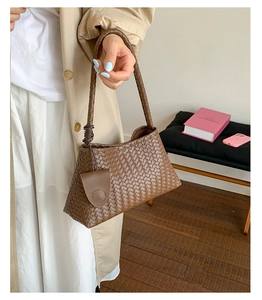 Detail of a brown woven texture shoulder bag with matching round charm and top handle