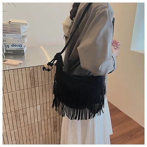 Detail of black suede tassel shoulder bag featuring decorative wooden beads on the strap