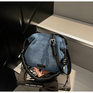 Close-up of pleated denim cloud bag featuring leather wrapped handles and textured fabric