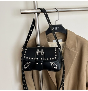 Detail of black punk shoulder bag with silver studs and adjustable metal eyelet strap