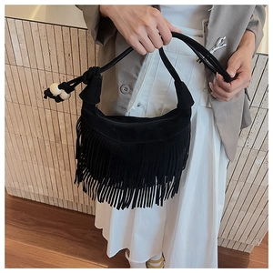 Close-up of black suede tassel shoulder bag with decorative wooden beads and fringe