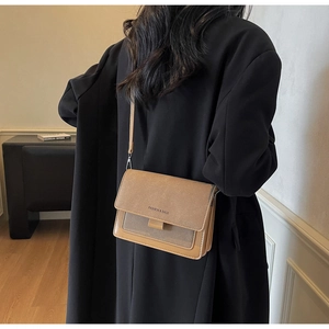 Close-up of a two-tone crossbody flap bag in brown and beige with thin shoulder strap
