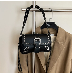 Detail of black punk shoulder bag with silver studs and metal eyelet wide strap
