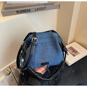 Close-up of denim bucket bag showing pleated texture and spiral black handle detail