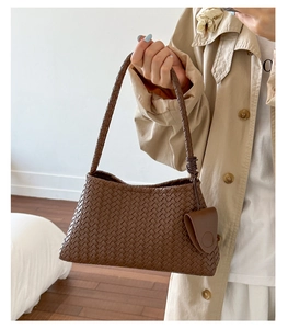 Detailed close-up of dark brown woven leather shoulder bag with a matching small pouch