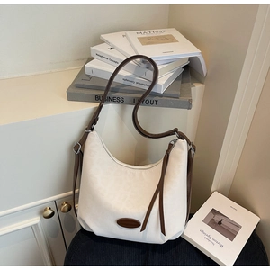 Detail of a minimalist cream hobo bag with adjustable brown strap and metal buckle