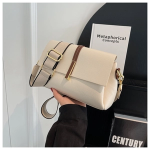 Detail of warm beige pebble leather crossbody bag with wide strap and gold hardware