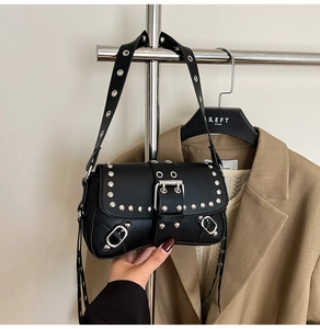 Detail of black punk shoulder bag with silver studs and oversized metal buckle closure