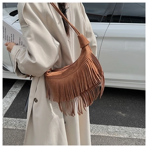 Close-up of brown suede moon bag featuring long fringe tassels and slim shoulder strap