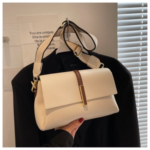Detail of cream pebbled leather crossbody bag with wide canvas strap and gold buckle