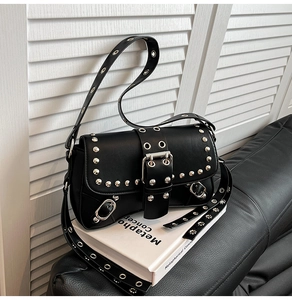 Detail of black punk shoulder bag featuring silver rivets and large decorative buckle