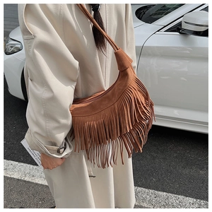 Detail of brown suede hobo bag featuring bohemian fringe tassels and zipper closure