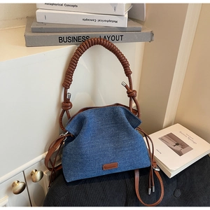 Detail of blue denim dumpling bag with pleated texture and brown braided leather handle