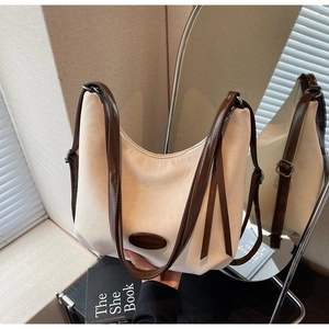 Detail of off-white hobo bag with brown leather strap and silver buckle in home setting