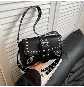 Detail of black punk shoulder bag featuring silver rivets and wide belt buckle strap