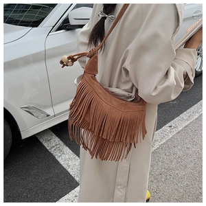 Detail of vintage brown suede shoulder bag with long fringes and beaded strap accents
