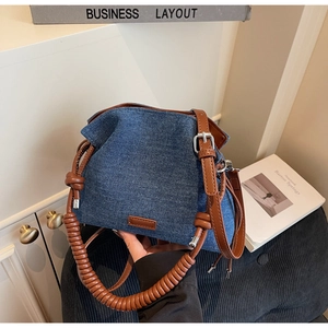 Detail of denim bucket bag with spiral woven handle and adjustable leather strap