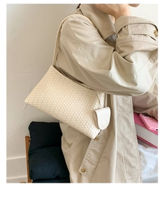 Detail of a beige woven shoulder bag with a mini side pouch on a trench coat model