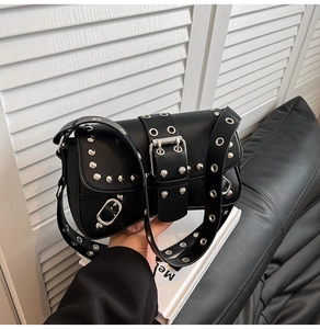Close-up of black leather handbag featuring silver studs and adjustable metal grommet strap