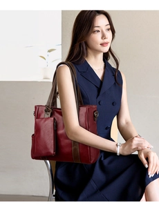 Model wearing a large burgundy faux leather tote bag with contrasting brown straps