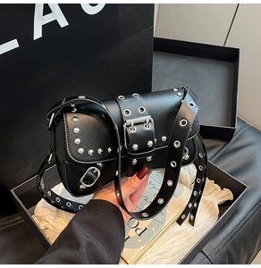 Detailed view of punk black leather shoulder bag with silver rivets and metal eyelets
