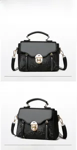Close-up of black snake-embossed leather handbag with gold twist lock and smooth top handle