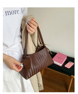 Detail of dark brown woven leather texture on a crescent shoulder bag with round charm