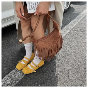 Close-up of brown suede hobo bag featuring bohemian tassels and decorative wooden beads