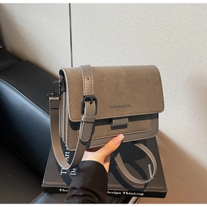 Dettaglio borsa a tracolla grigia in scamosciato con scritta Fashion & Bags e tracolla