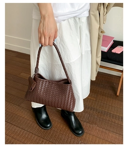 Detail of dark brown leather woven handbag featuring wide Intrecciato pattern and knot detail