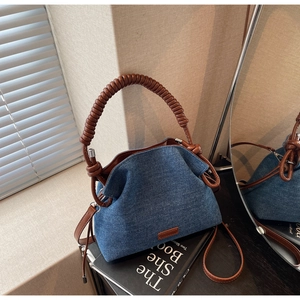 Macro detail of denim texture and brown spiral handle on a pleated bucket bag
