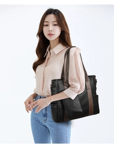 Detail of soft leather tote bag showing color-block brown straps and side pocket texture