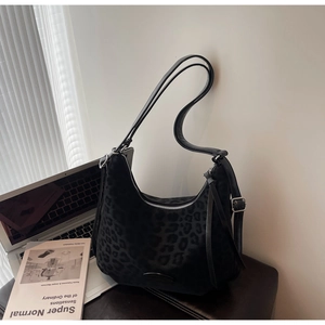 Detail of a black leopard print hobo bag with fringe tassel and leather strap handles