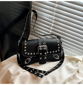 Detail of punk style black leather bag featuring silver studs and adjustable metal grommet strap