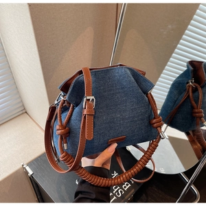 Detail of blue denim bucket bag with spiral braided handle and brown leather straps